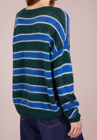 Groen- en blauwgestreepte trui met losse pasvorm, zachte textuur, brede halslijn en lange mouwen. Kenmerkt zich door verschillende strookbreedtes en lichte pluizigheid.