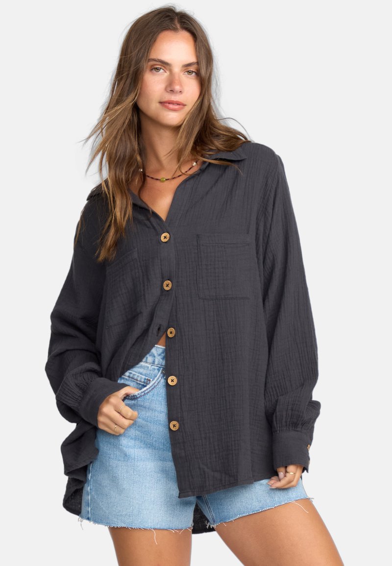 Zwarte button-up shirt van gestructureerde stof, voorzien van houten knopen, een kraag en een borstzak, gecombineerd met denimshorts.