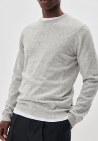 Sivi pleteni pulover napravljen od mekog materijala, s okruglim izrezom, rebrastim manžetama i donjim dijelom, s suptilnom teksturom kroz cijeli pulover.