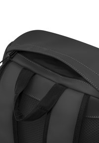 Svart ryggsäck med en slät, matt yta, strukturerad meshdetaljering och kontrasterande vit sömnad. Inkluderar ett handtag på toppen och en dragkedja.