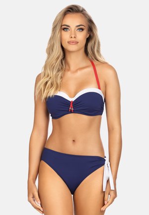 Navy bikini z białymi kropeczkami, biustonosz z drutem, czerwone ramiączka i dół związywany z boku. Gładka faktura i dopasowany krój.