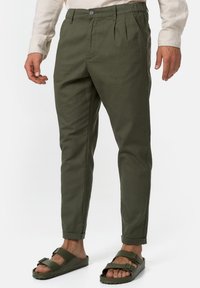Pants levejä oliivinvihreitä, etupleittiset ja kevyttä kangasta. Yhdistettynä avonaisiin sandaaleihin, joissa on solki.