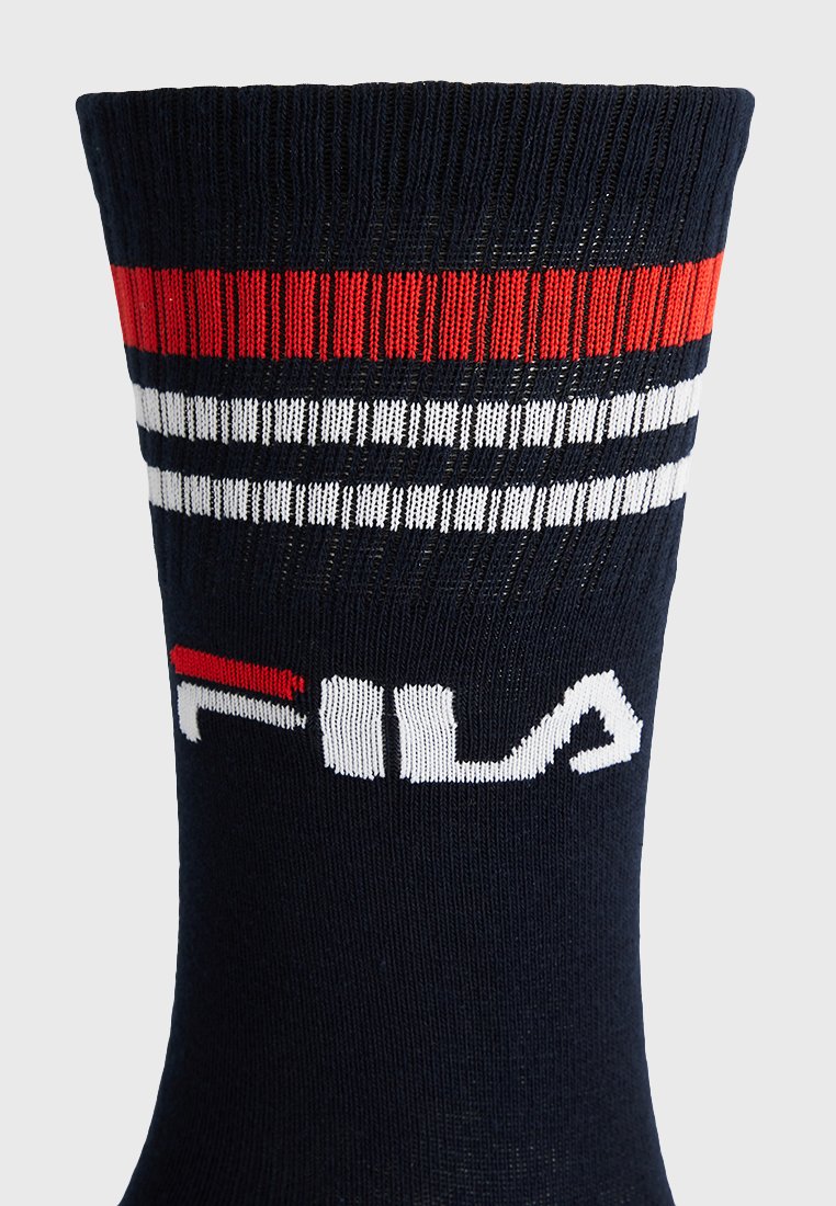 Granatowa skarpetka z czerwono-białymi paskami na górze oraz częściowo widocznym białym i czerwonym logo "FILA" poniżej pasków.