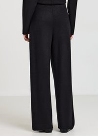 Schwarze, weit geschnittene Hose aus weichem Stoff, mit hohem Bund und wenigen Nähten, die ein glattes, strukturiertes Erscheinungsbild bietet.