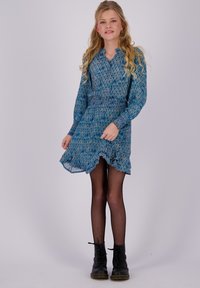 Blau gemustertes Kleid mit langen Ärmeln, gerüschtem Saum und gerafftem Bund. Tragen mit schwarzen Netzstrumpfhosen und Schnürstiefeln.