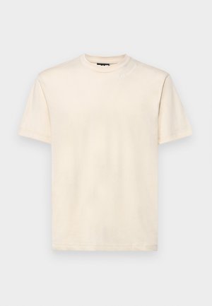 T-shirt in cotone beige chiaro con scollatura tonda, maniche corte e un logo ricamato discreto sulla spalla. Texture liscia.