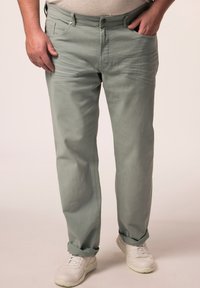 Vihreät puuvillahousut, joissa on sileä pinta, viisi taskua ja käännetyt lahkeet, yhdistetty valkoisiin lenkkitossuihin.