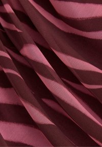 Let mesh stof med et let vægt og et pink og mørk burgunder stribet mønster, med en blød tekstur og en strømline udseende.