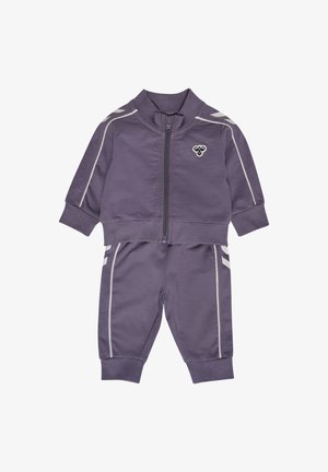 Survêtement violet en tissu lisse ; comprend une veste zippée, des poignets élastiques et un pantalon assorti avec des rayures blanches sur les côtés et un logo.