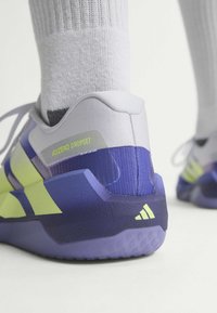 Κοντινό πλάνο ενός μωβ και λαιμ παπουτσιού Adidas Adizero Dropset που φοριέται με λευκές κάλτσες, εστιάζοντας στη φτέρνα και τις λεπτομέρειες της μάρκας.