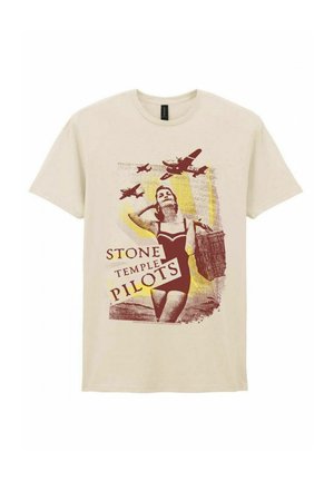 Nainen vintage-uimapuvussa kantaa pajukoria, jossa on kolme lentokonetta lentämässä yläpuolella, beige T-paidassa teksti "Stone Temple Pilots".