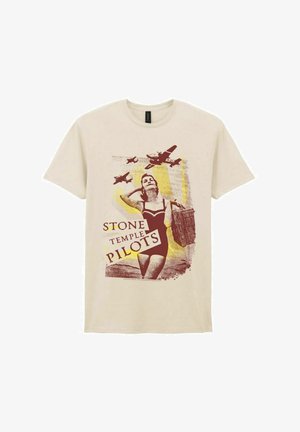 Mujer con traje de baño vintage llevando una cesta de mimbre mientras tres aviones vuelan sobre ella, con el texto "Stone Temple Pilots" en una camiseta beige.