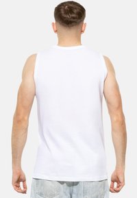 Débardeur sans manches blanc, en coton lisse, avec un col rond classique et une coupe décontractée, montrant la vue de dos sur un fond clair.