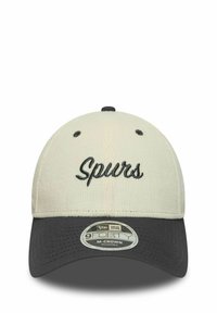 Cremefarbener Hut mit schwarzem Schirm; gesticktes "Spurs" in Schriftzug auf der Vorderseite. Verfügt über einen verstellbaren Riemen, eine strukturierte Form und einen strukturierten Stoff.