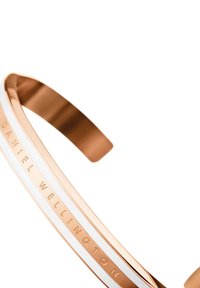 Bracciale a manica in oro rosa con una striscia in smalto bianco e incisione del testo "DANIEL WELLINGTON", con una finitura liscia e lucida.