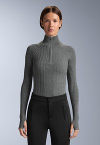 Grå ribbade turtleneck-tröja med halv dragkedja, figurnära silhuett, lång ärm med tumhål, kombinerad med svarta figurnära byxor.