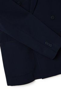 Blazer doppiopetto blu navy in tessuto morbido, con revers a punta, due bottoni frontali e tasca applicata. Dettaglio del polsino a tre bottoni.