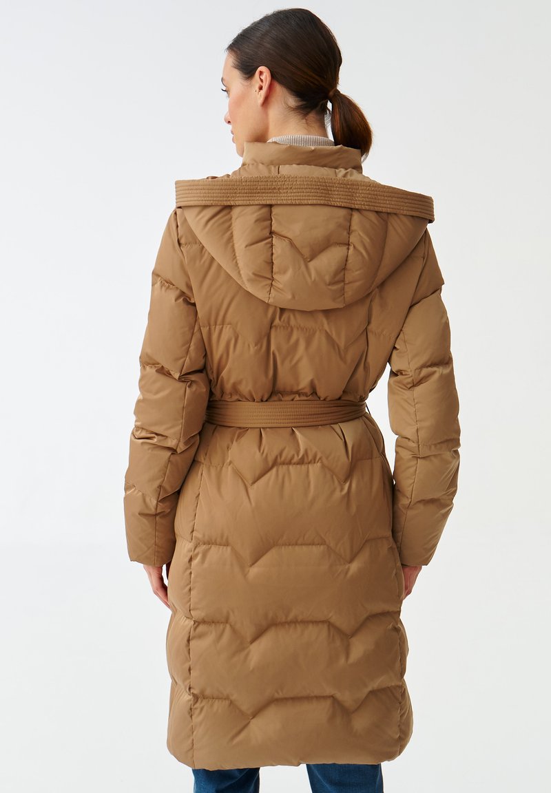 Brązowa kurtka puchowa z paskiem, kapturem i pikowanym wzorem. Posiada teksturowany kołnierz i średniej długości kroj. Talia jest zwężona.