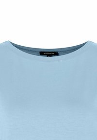 Helles blaues Oberteil aus glattem Stoff, mit Rundhalsausschnitt und kurzen Ärmeln. Etikett zeigt die Marke "MORE & MORE" und Größe 36.