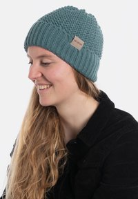 Gebreide beanie in teal, met een gestructureerd patroon en een geribbelde rand. Inclusief een klein leren logo label aan de zijkant.