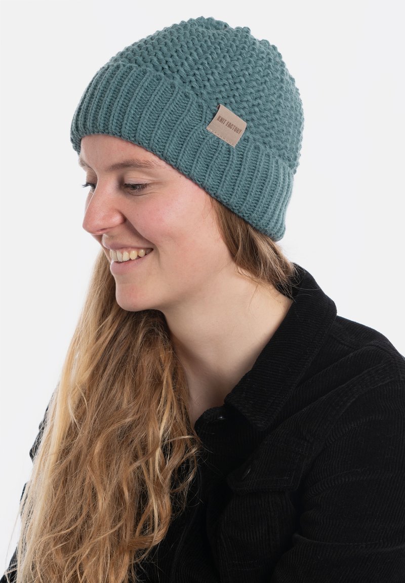 Gebreide beanie in teal, met een gestructureerd patroon en een geribbelde rand. Inclusief een klein leren logo label aan de zijkant.