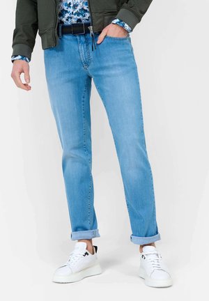Light blue denim jeans with a straight fit, rolled cuffs, and a classic five-pocket design. Styled with a black belt and white sneakers.
