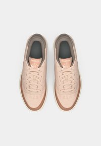 Ροζ αθλητικά παπούτσια Reebok με κορδόνια, διάτρητη μύτη, αντίθετες καφέ λεπτομέρειες και μαλακή επένδυση. Χαμηλή σόλα με ανάγλυφη πρόσφυση.