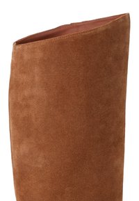 Botte en daim marron haute jusqu'au genou avec un bord supérieur légèrement incliné et une doublure intérieure lisse, présentant une texture douce et un design épuré.