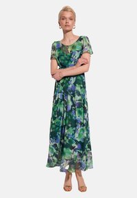Maxi sukienka z przezroczystego, lekkiego materiału w kwiatowy wzór w odcieniach zieleni i niebieskiego. Posiada krótkie rękawy oraz zwiewny krój.