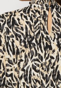 Short-sleeve dress featuring a black, grey, and beige abstract pattern, with a gathered neckline and a keyhole opening at the back.