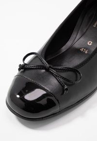 Black ballet flat with a glossy patent leather toe cap, textured black leather body, and a bow accent at the front. Size 41½.