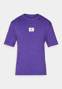 Lilla bomulds T-shirt med rund hals, korte ærmer og en struktureret overflade. Har et lille hvidt logopatch på fronten.