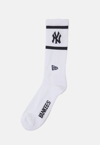 Calcetín deportivo blanco con rayas azules y logo de los New York Yankees. Textura acanalada y "YANKEES" impreso en azul en la suela.