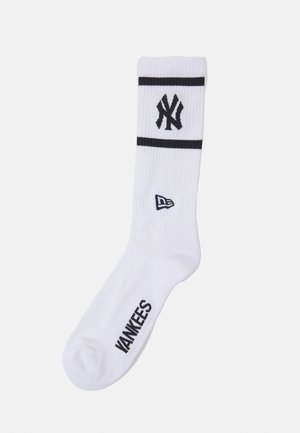 Weiße Sportsocke mit marineblauen Streifen und New York Yankees-Logo. Rippstruktur und „YANKEES“ in Marineblau auf der Sohle gedruckt.
