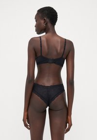Black lingerie set featuring a scalloped edge bra with adjustable straps and hook closure, paired with lace-accented panties.