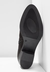 Czarne zamszowe botki za kostkę z okrągłym noskiem, zamkiem błyskawicznym z boku oraz teksturowaną gumową podeszwą dla lepszej przyczepności. Rozmiar 37 oznaczony na podeszwie.