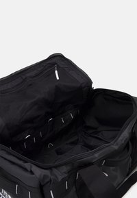 Mustaväri matkalaukku, joka on valmistettu kestävästä kankaasta. Laukussa on vetoketjullinen pääosasto, jossa on verkkotaskuja ja sisäisiä koukkuja järjestämisen helpottamiseksi.