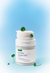 Contenedor transparente con almohadillas de tóner blancas, etiquetado "EQUALBERRY PISCINA". Hoja verde de acento y gotas sobre las almohadillas. Fondo azul suave.