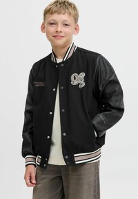 Giubbotto varsity nero con maniche in pelle texture, polsini a costine a righe bianche e logo ricamato. Presenta una chiusura frontale a bottoni a pressione e una vestibilità morbida.