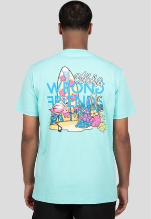 Camiseta de algodón azul claro con un diseño gráfico colorido que incluye elementos tropicales, como un flamenco, flores y tablas de surf en la parte posterior.