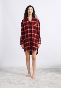 Κόκκινο και μαύρο καρό φανελένιο πουκάμισο, με μακριά μανίκια, κουμπωτό μπροστινό μέρος και λεπτομέρεια λογότυπου στο στήθος, με ελαφρώς κυρτή γραμμή στο κάτω μέρος και άνετη εφαρμογή.