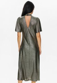 Metallic green mid-length dress with short puff sleeves and a cut-out back. Textured fabric with a smooth sheen and flowing silhouette.