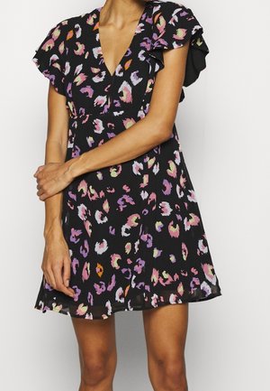 Schwarzes Kleid mit buntem abstraktem Blumenmuster, kurzen Flatterärmeln und V-Ausschnitt, getragen von einer Person mit verschränkten Armen.