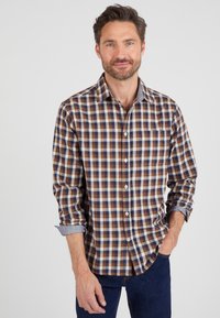 Camicia a quadri marrone e blu con maniche arrotolate e colletto a contrasto, dotata di chiusura a bottoni sul davanti e una tasca sul lato sinistro.