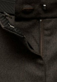 Pantaloni grigi scuri con chiusura a zip e dettagli con bottone, realizzati in un tessuto strutturato e con un design a gamba dritta.