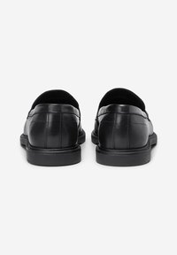 Sorte læder slip-on dress sko med syet detaljer, set fra bagfra på en hvid baggrund.