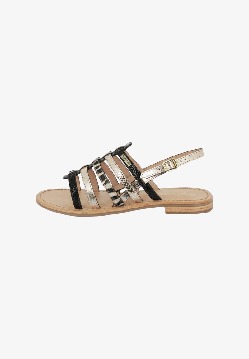 Sandalia con tiras, base de cuero beige, correas texturizadas negras, detalles metálicos y un tacón bajo de madera. Hebilla ajustable en la correa del tobillo.
