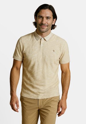 Beige poloshirt met bladerenpatroon, korte mouwen, kraag, twee-knopsluiting en bijpassende beige korte broek, gedragen door een mannelijke modelo.