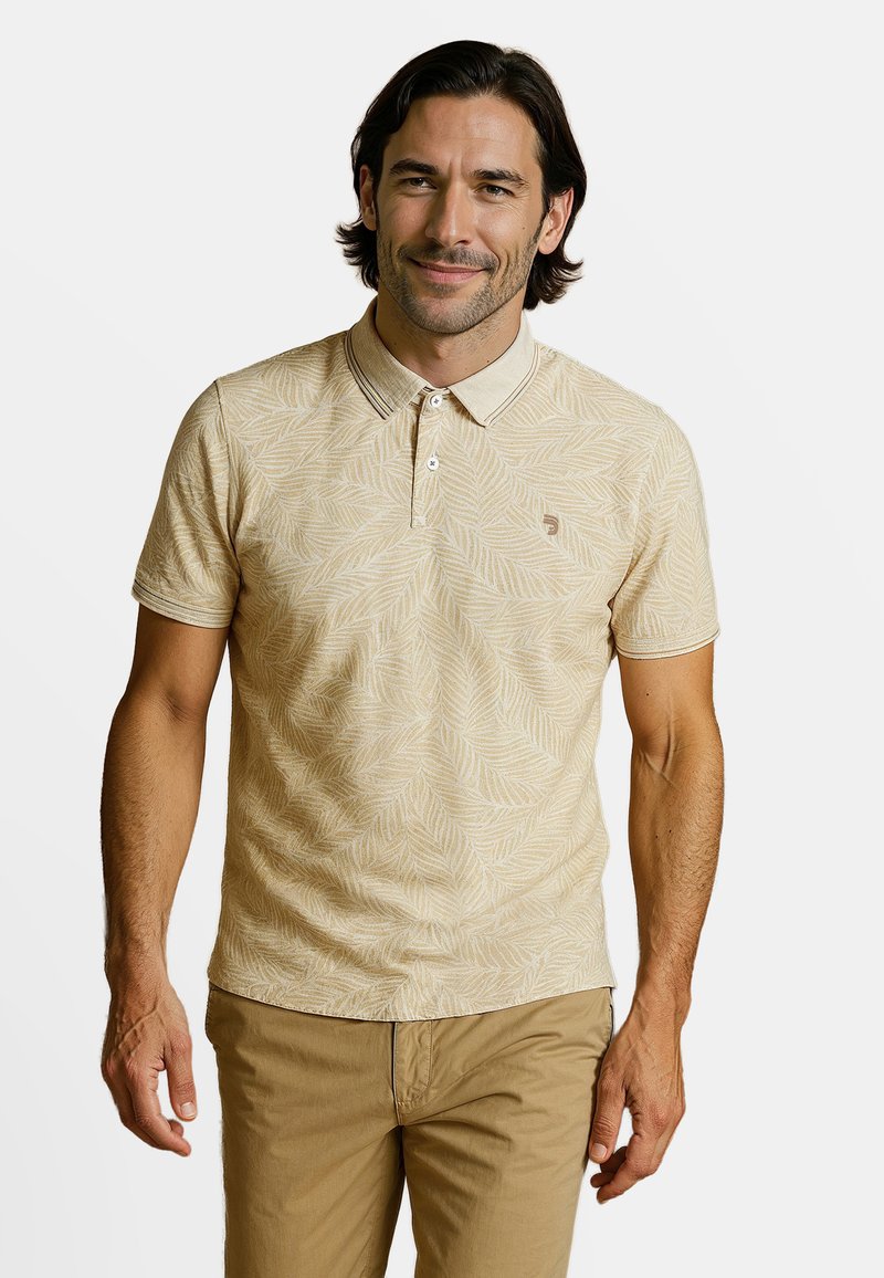 Beige poloshirt met bladerenpatroon, korte mouwen, kraag, twee-knopsluiting en bijpassende beige korte broek, gedragen door een mannelijke modelo.