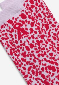 Rosa Socken mit einem roten Leopardenmuster, einem strukturierten Strickdesign und einem auffälligen Buchstaben "A" an der Seite.